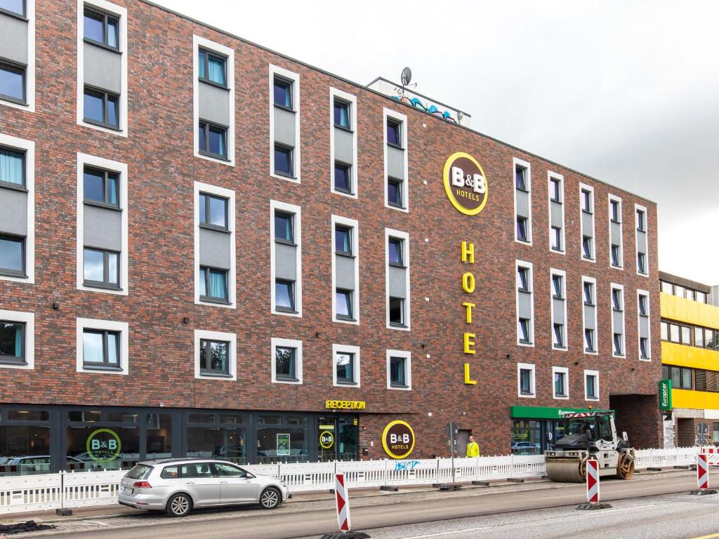 ein großes Backsteingebäude mit einem davor geparkt in der Unterkunft B&B Hotel Hamburg-Wandsbek in Hamburg