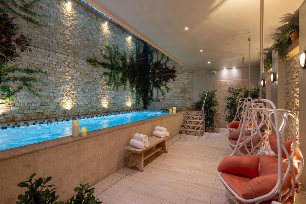 a swimming pool in a room with chairs next to it at Royal Madeleine Hotel & Spa in Paris