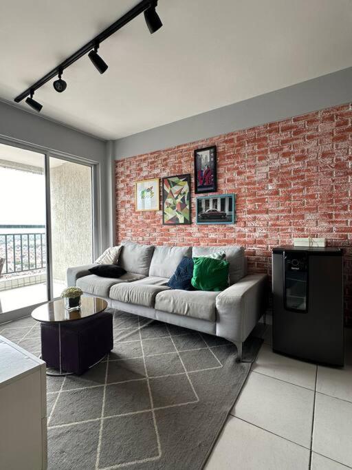 a living room with a couch and a brick wall at Apto melhor localização do Cocó in Fortaleza