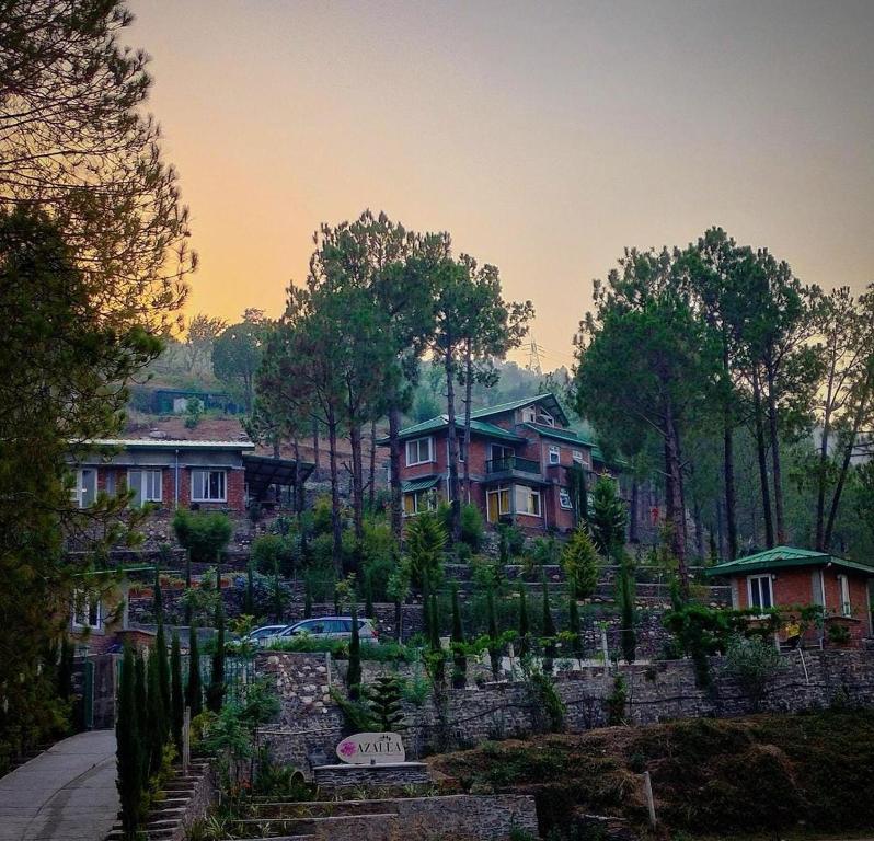 a garden in front of some houses with trees at Azalea in Jajal