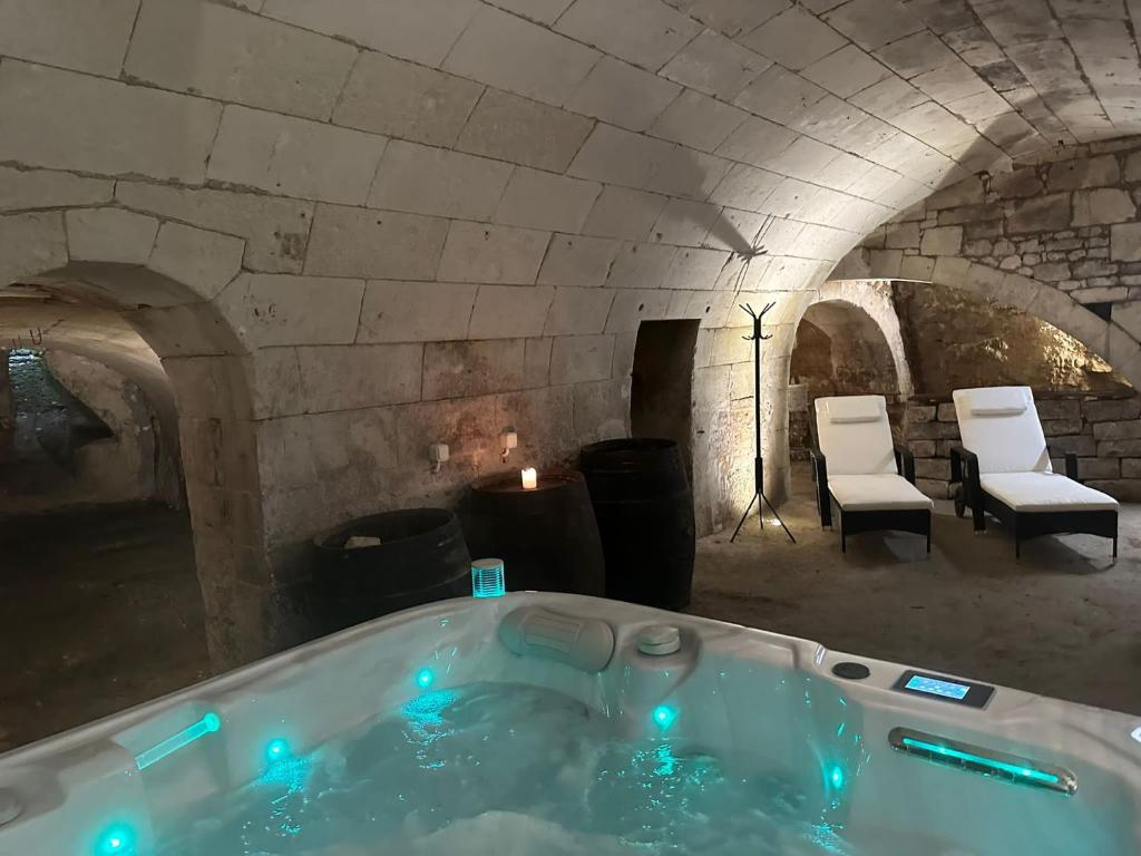 a bath tub in a stone room with chairs at GITE AU BOOM COEUR forfait Spa, Dîner & Petit-déjeuner inclus in Tourtenay