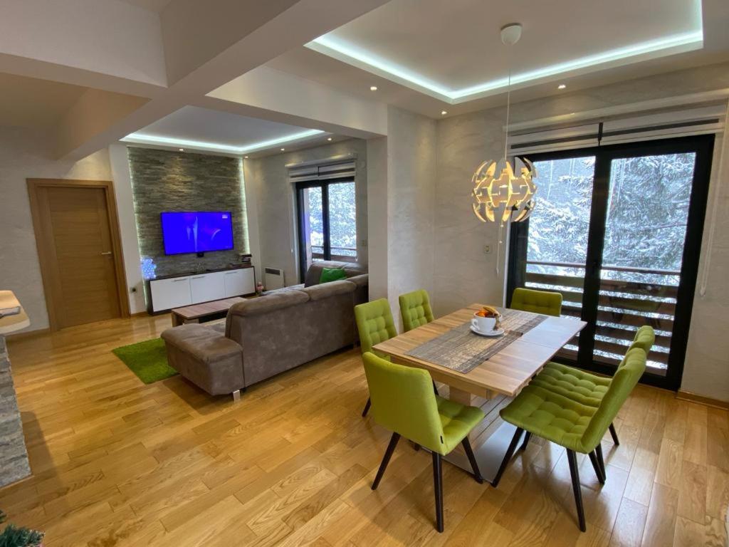 ein Wohnzimmer mit einem Tisch und grünen Stühlen in der Unterkunft Apartman Dunja-Vila Pekovic Zlatibor in Zlatibor