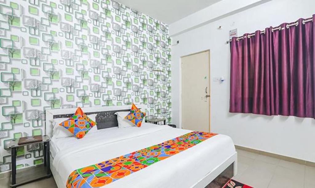 a bedroom with a large bed with a colorful blanket at FabExpress Ashiyana Inn in Patna