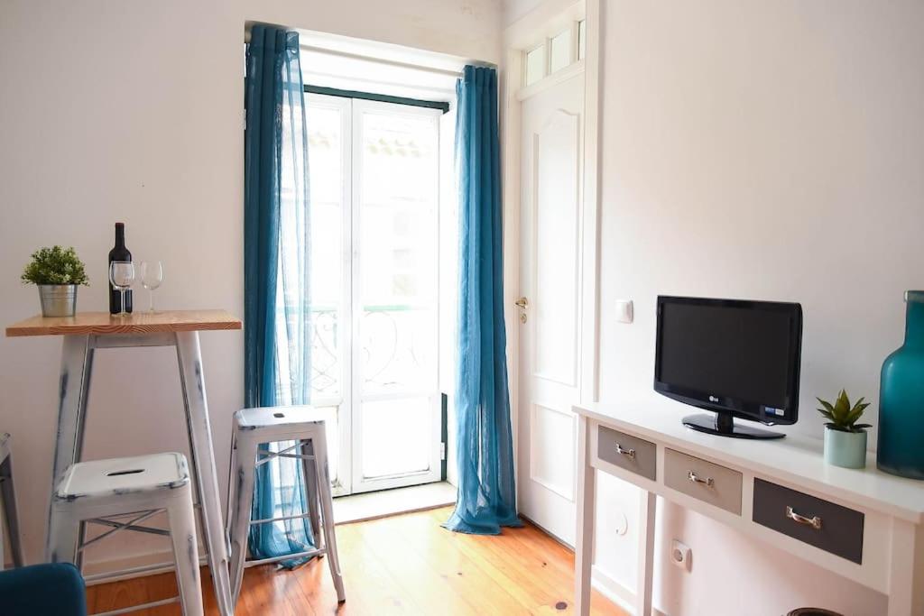 een woonkamer met een televisie en een raam bij Lisbon Historic Center Apartment in Lissabon