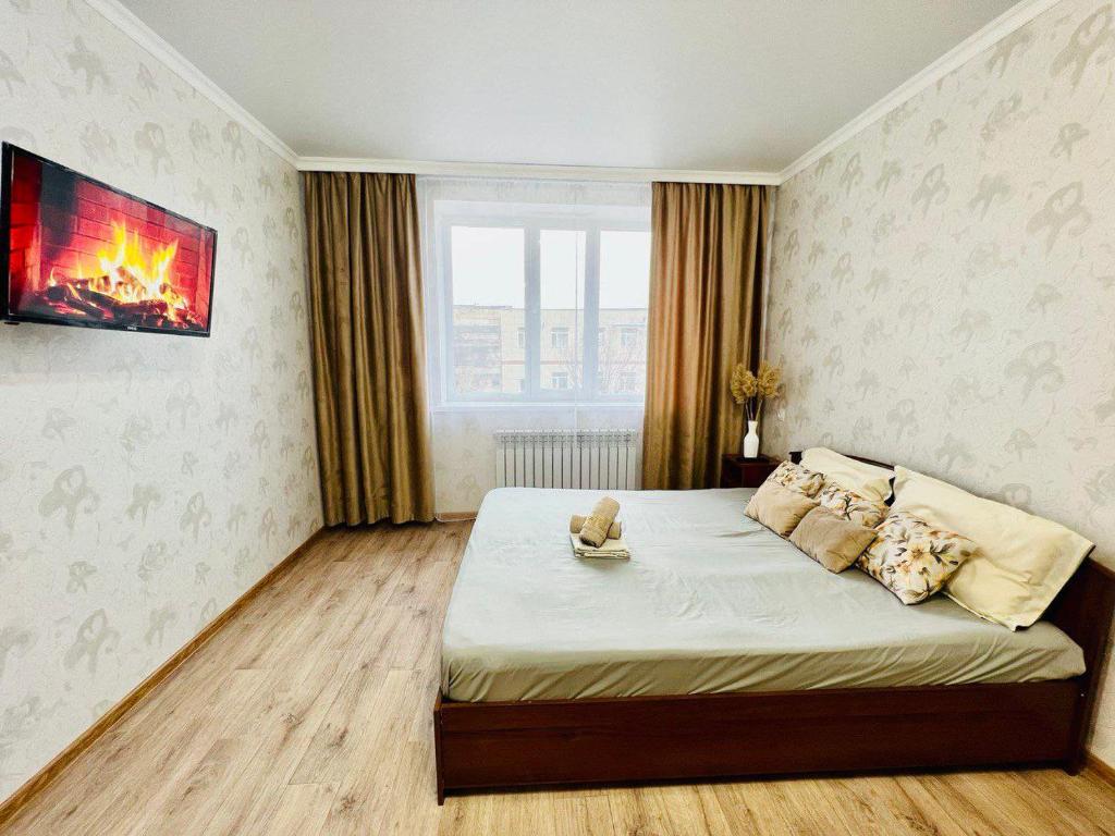 卡拉干達的住宿－ЖК Алтын бесік，卧室配有一张大床,墙上有火炉