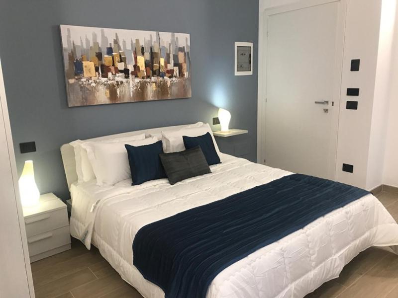una camera da letto con un grande letto bianco con cuscini blu di La Corte di Firenze Bed and Breakfast a Firenze