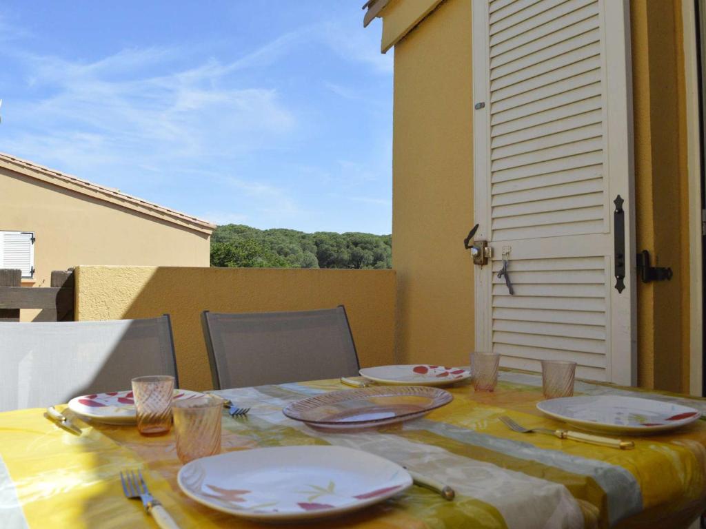 - une table avec des assiettes et des ustensiles sur le balcon dans l'établissement Appartement Climatisé à 450m Plage avec Terrasse et Parking Privé - 7 Couchages, Cap d'Agde - FR-1-249-44, au Cap d'Agde
