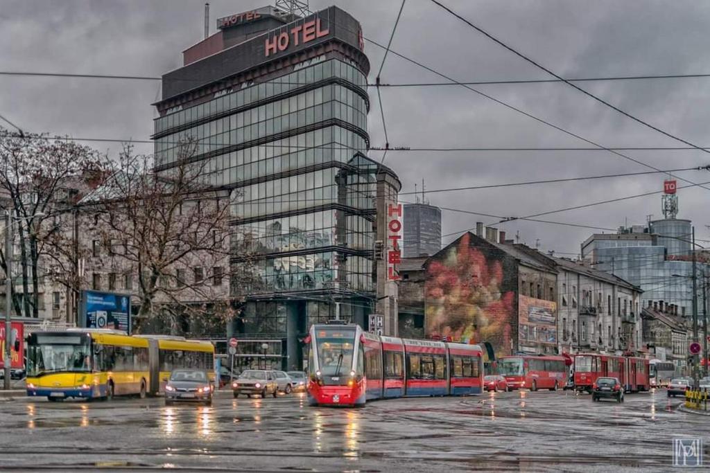 a city with buses and cars on a street at Design Hotel Mr President in Belgrade