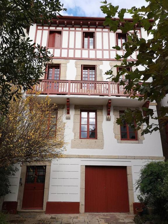 - un bâtiment avec des portes rouges et un balcon dans l'établissement Saint-Jean de Luz, appartement vue mer 4 couchages, à Sainte-Barbe