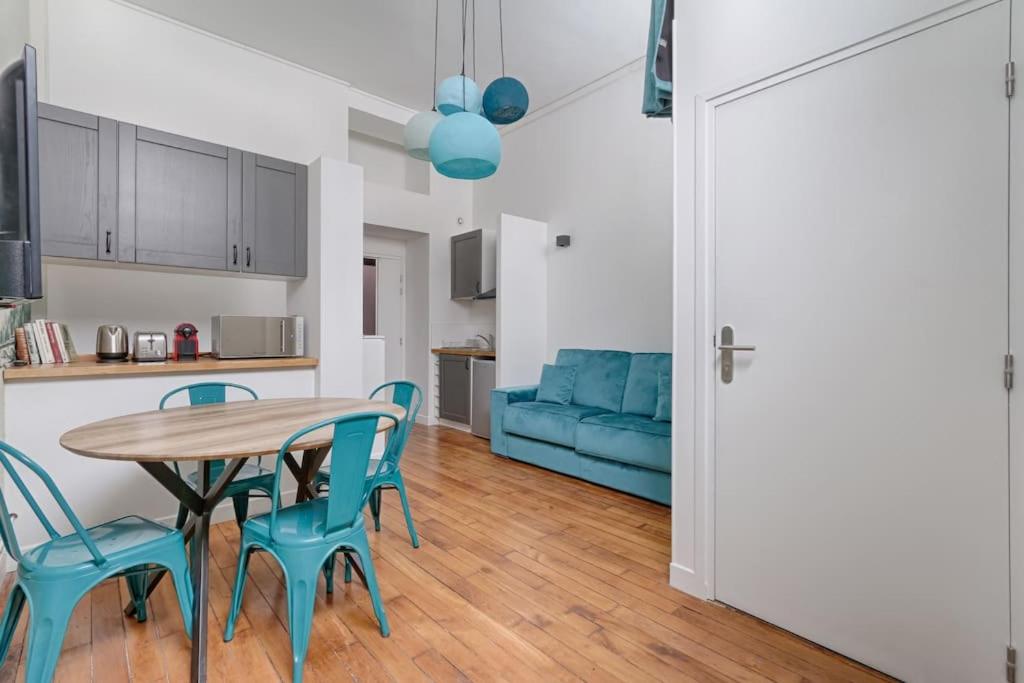 une cuisine avec une table, des chaises et un canapé bleu dans l'établissement Luxury LOFT 6P - Arc de Triomphe, à Paris