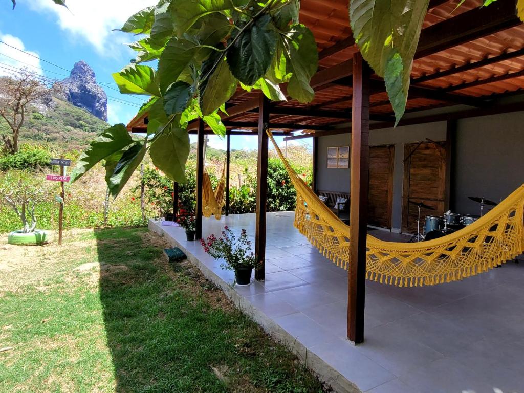 a view of a house with a hammock in the yard at Batera House Noronha in Fernando de Noronha