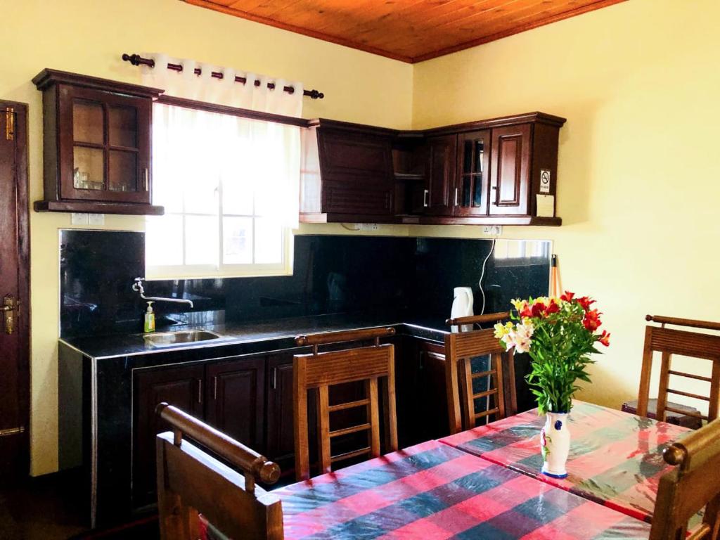 una cucina con un tavolo con un vaso di fiori sopra di Shevyhaws a Nuwara Eliya
