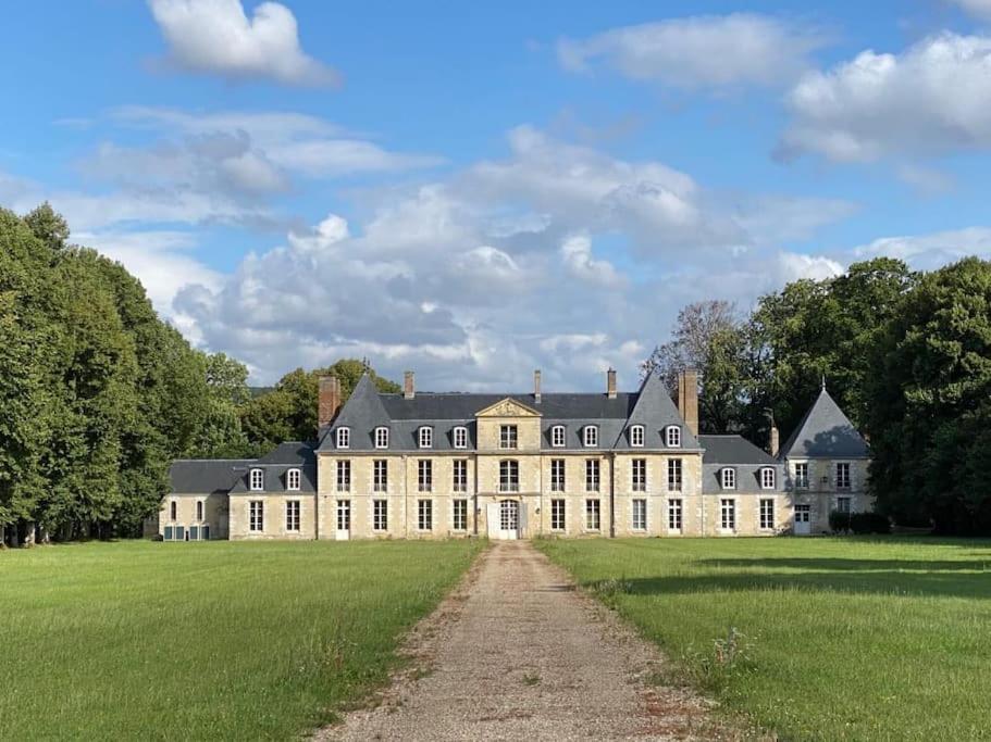 ein großes weißes Haus mit einem Feld und Bäumen in der Unterkunft Chateau de Tosny 
