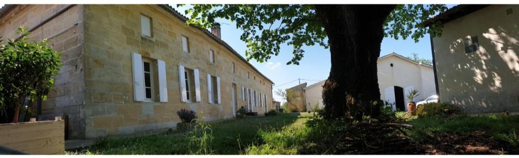 an old brick building with a tree next to it at Halte au beau Millet in Coutras