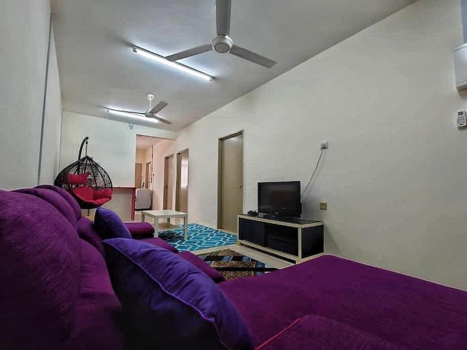 a living room with a purple couch and a tv at Nourina Homestay Gambang in Gambang