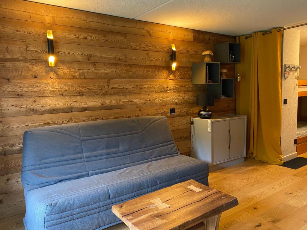 ein Wohnzimmer mit einem blauen Sofa und einem Tisch in der Unterkunft Superbe studio au pied des pistes in La Morte