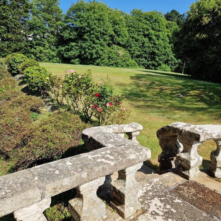 a stone bench with a park in the background at château de Locquéran Pierres et filets bleus in Plouhinec