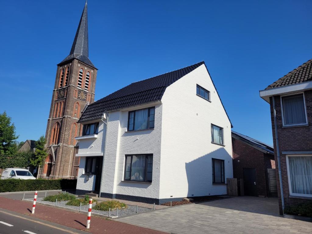 ein weißes Gebäude mit einem Kirchturm im Hintergrund in der Unterkunft Het Wit Huys in Born