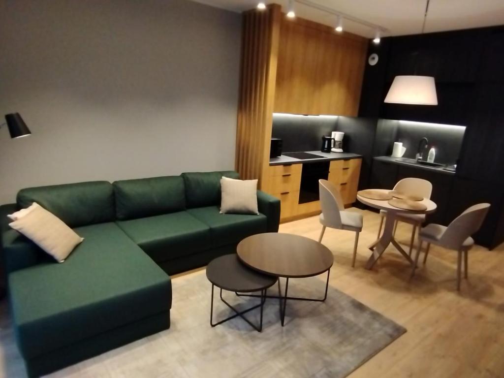 a living room with a green couch and a table and chairs at Fantastyczny apartament Lotnisko in Poznań