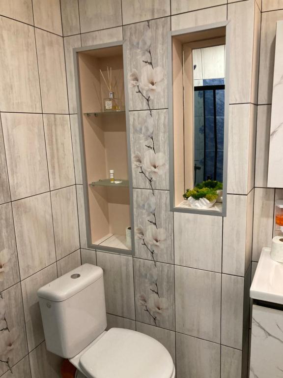 a bathroom with a toilet and a wall with flowers at Уютен апартамент Мечта in Vratsa