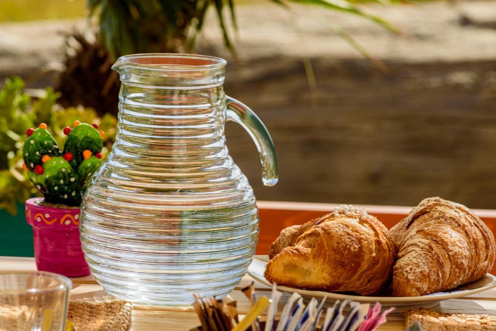 a glass jug and a plate of bread and croissants at B&B Fermata 106 da Carolina in Siculiana Marina