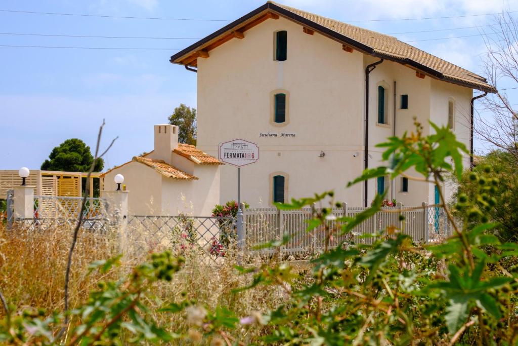 ein weißes Haus mit einem Zaun davor in der Unterkunft B&B Fermata 106 da Carolina in Siculiana Marina