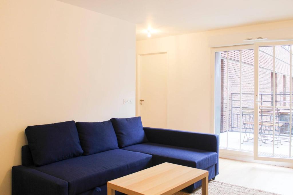 ein Wohnzimmer mit einem blauen Sofa und einem Tisch in der Unterkunft Quiet apartment near the Flea Market in Saint-Ouen