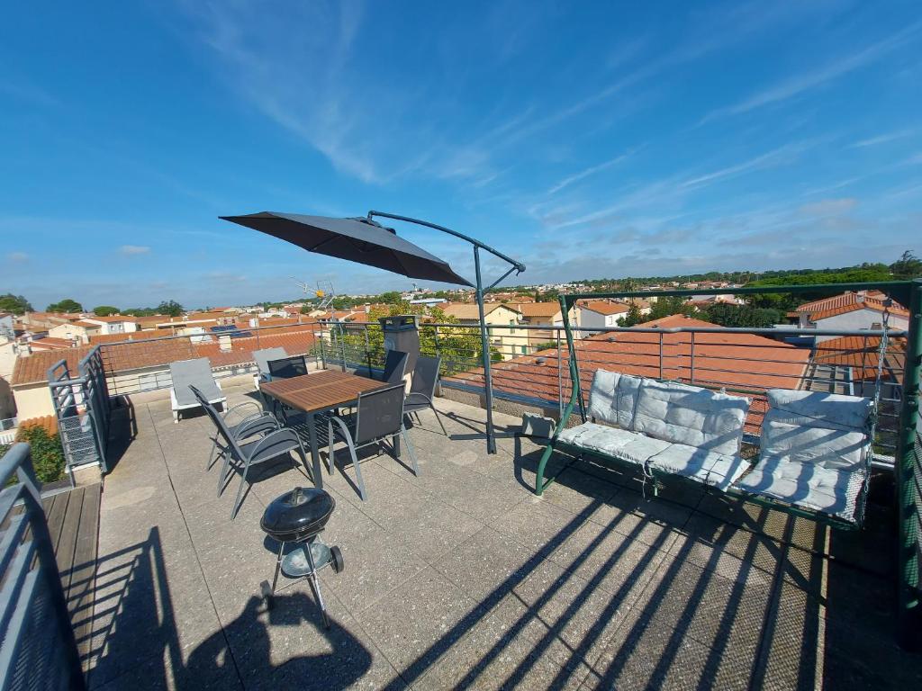 eine Terrasse mit einem Tisch, Stühlen und einem Sonnenschirm in der Unterkunft soleil catalan terrasse panoramique ok chéques vacances 4pers wifi 65m2 jardin parking 2ch 2km mer in Latour-Bas-Elne