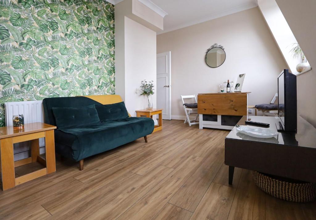 uma sala de estar com um sofá verde e uma mesa em Lovely flat in Notting Hill- 1 min to the tube em Londres