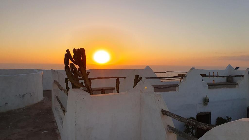 a sunset over the roofs of white buildings at Riad Sahara Sunset Beach Agadir in Douaïra