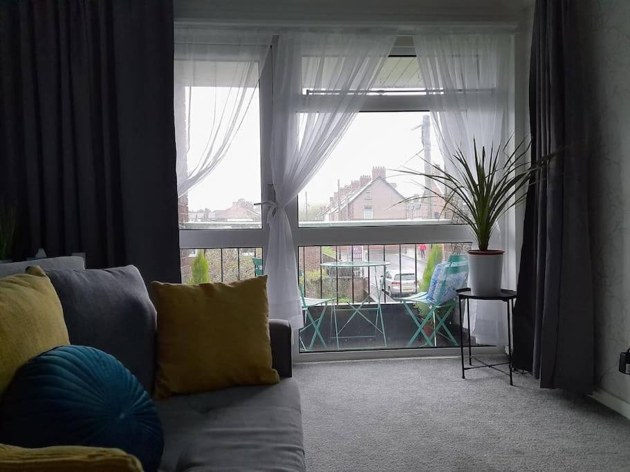 a living room with a couch and a large window at Cosy Apartment with Balcony and Breakfast in Bishop Auckland