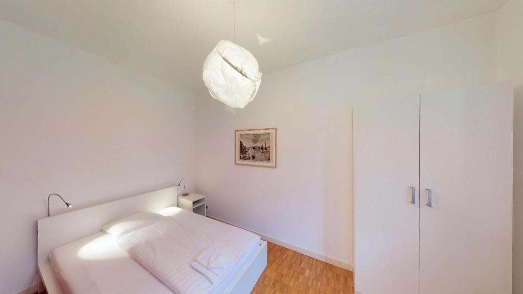 ein weißes Zimmer mit einem Bett und einer Lampe in der Unterkunft Unique Serviced Living @ Airport Line in Basel