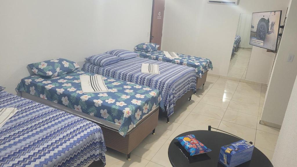a room with two beds and a table with a bedskirts at Suite Pajuçara in Maceió