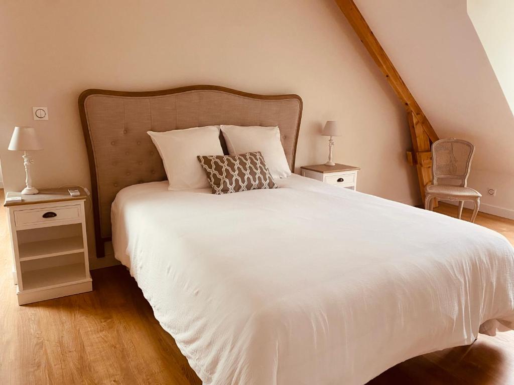 ein Schlafzimmer mit einem weißen Bett und zwei Nachttischen in der Unterkunft Le Domaine Des Trois Chênes 