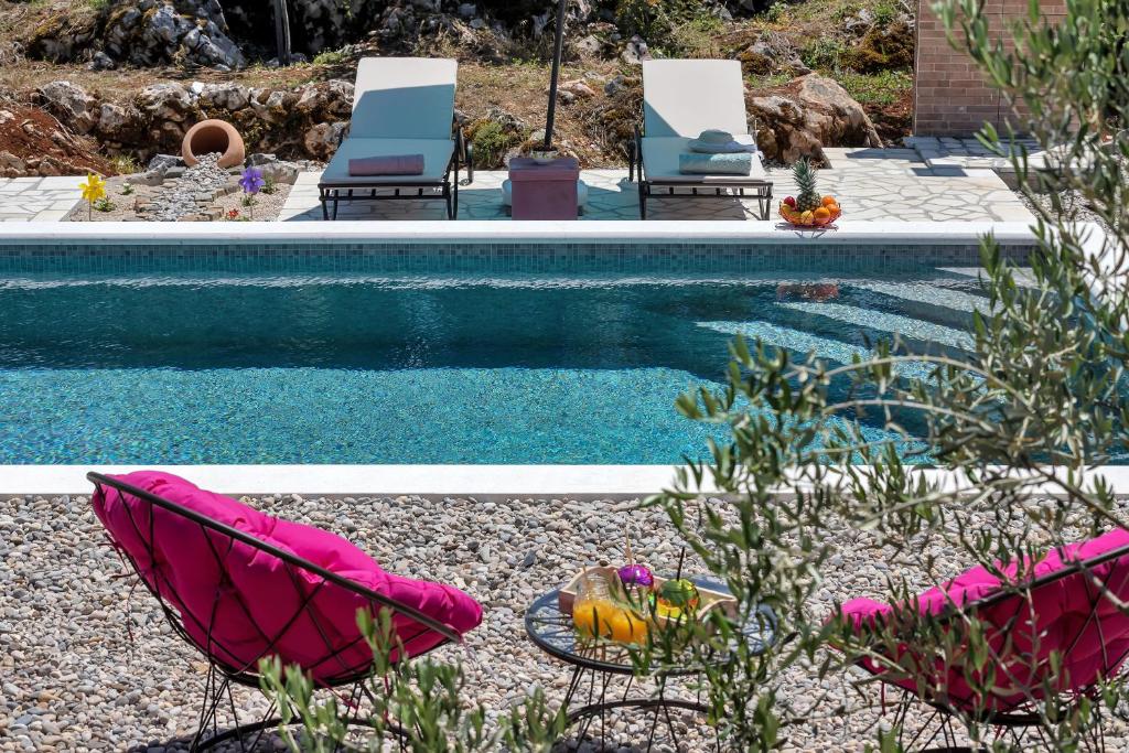 una piscina con 2 sillas y una mesa con fruta al lado en Holiday home Danica, en Ožići