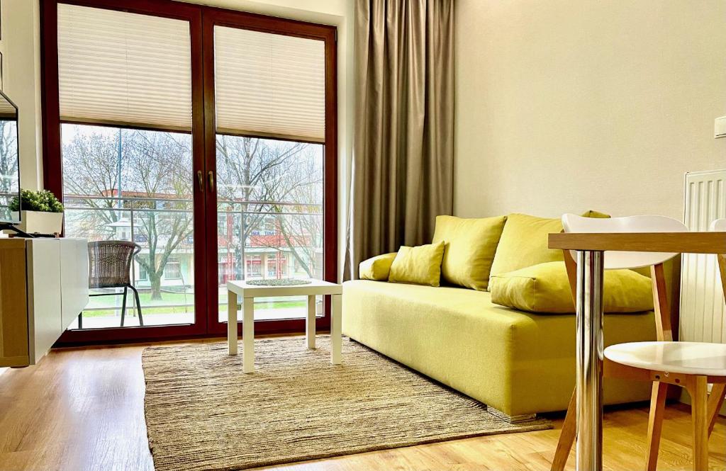 ein Wohnzimmer mit einem gelben Sofa vor einem Fenster in der Unterkunft Opera Park 23 by RENT4YOU in Olsztyn