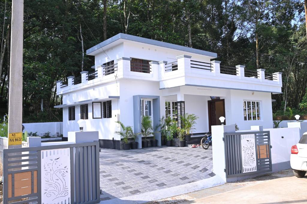 ein weißes Haus mit einem Zaun davor in der Unterkunft Holiday Villa - Your Second Home - Kothamangalam in Kotamangalam