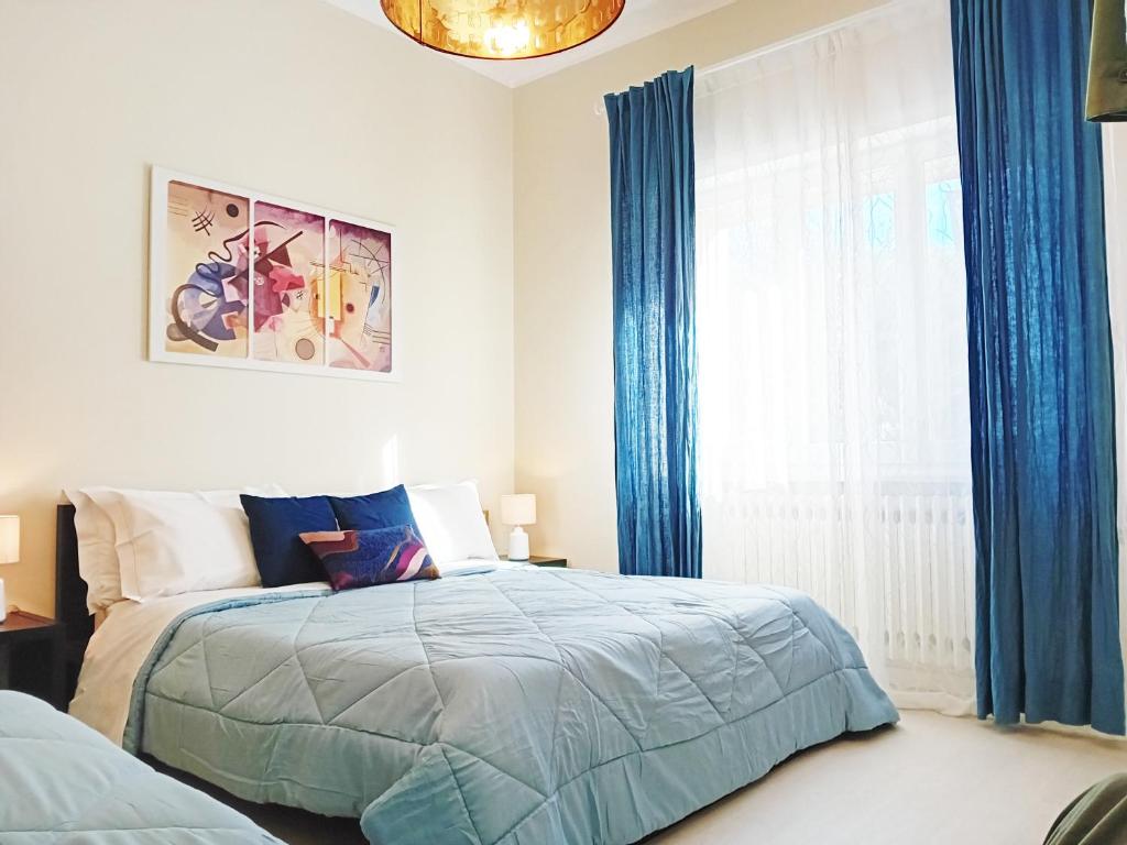 een slaapkamer met een bed en een raam met blauwe gordijnen bij CasaRava Sul Parco in Riccione