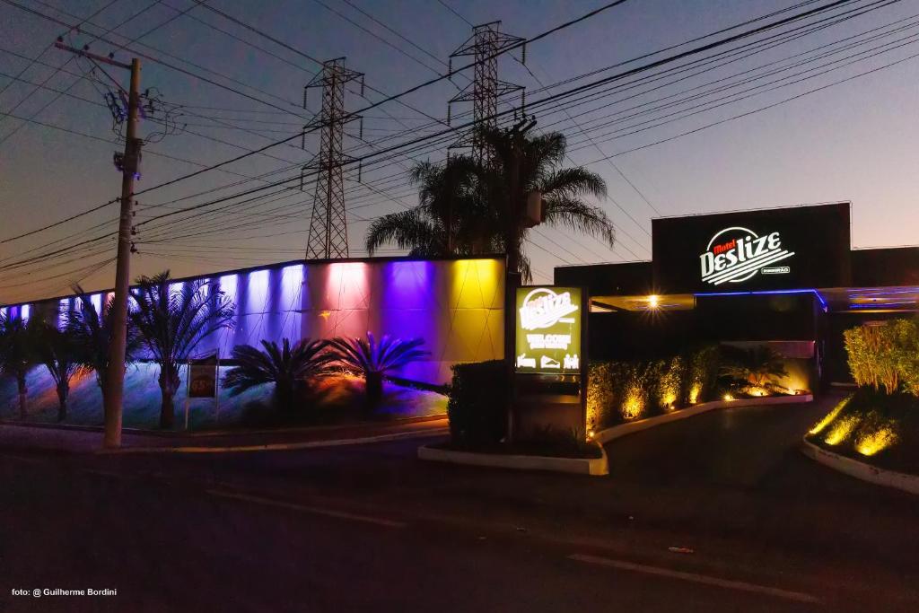 un bâtiment éclairé avec un panneau sur son côté dans l'établissement Motel Deslize Ribeirão Preto, à Ribeirão Preto