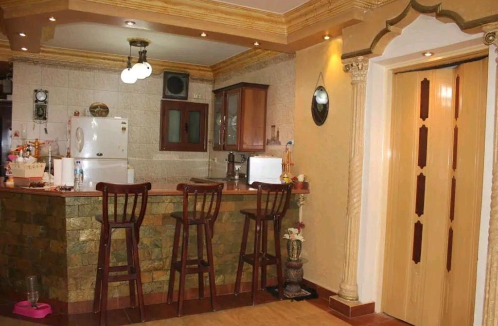 a kitchen with a bar with chairs and a refrigerator at شقه مفروشه مميزه in Cairo