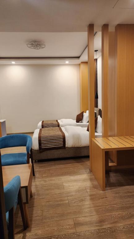a bedroom with a bed and a table and a chair at Prudential Hotel Nepal in Kathmandu