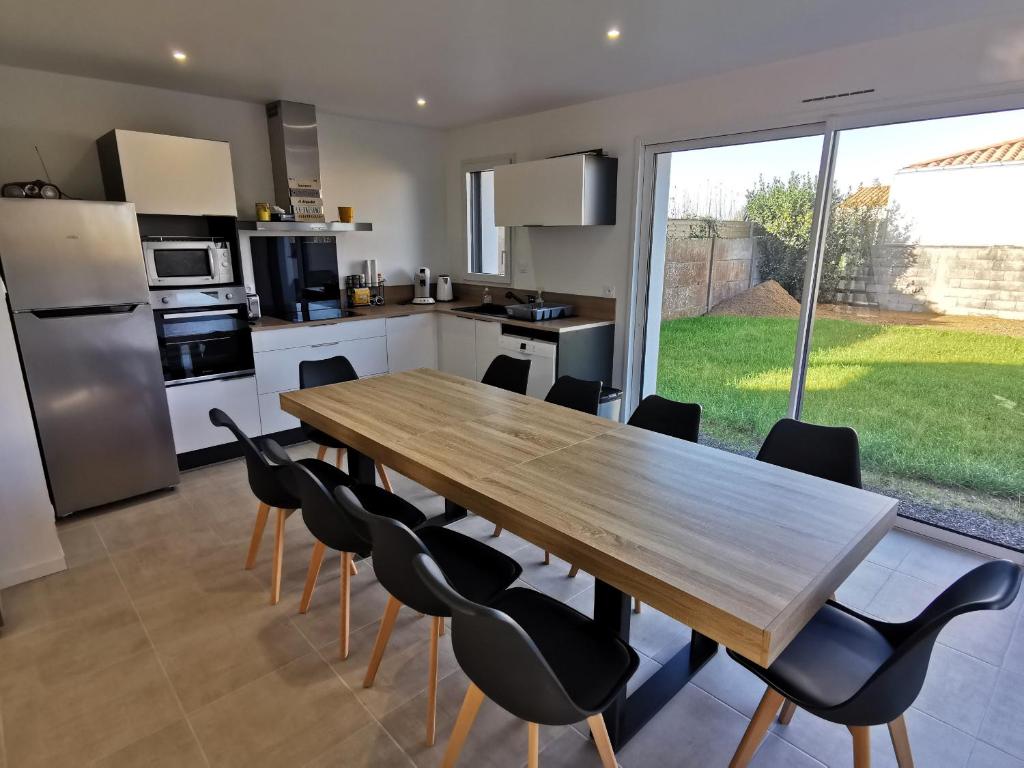 cocina grande con mesa de madera y sillas en La Maison Manole, en Jard-sur-Mer