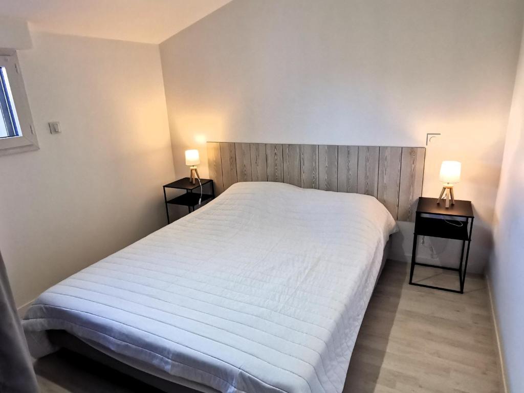 1 dormitorio con 1 cama blanca y 2 mesitas de noche en La Maison Manole, en Jard-sur-Mer