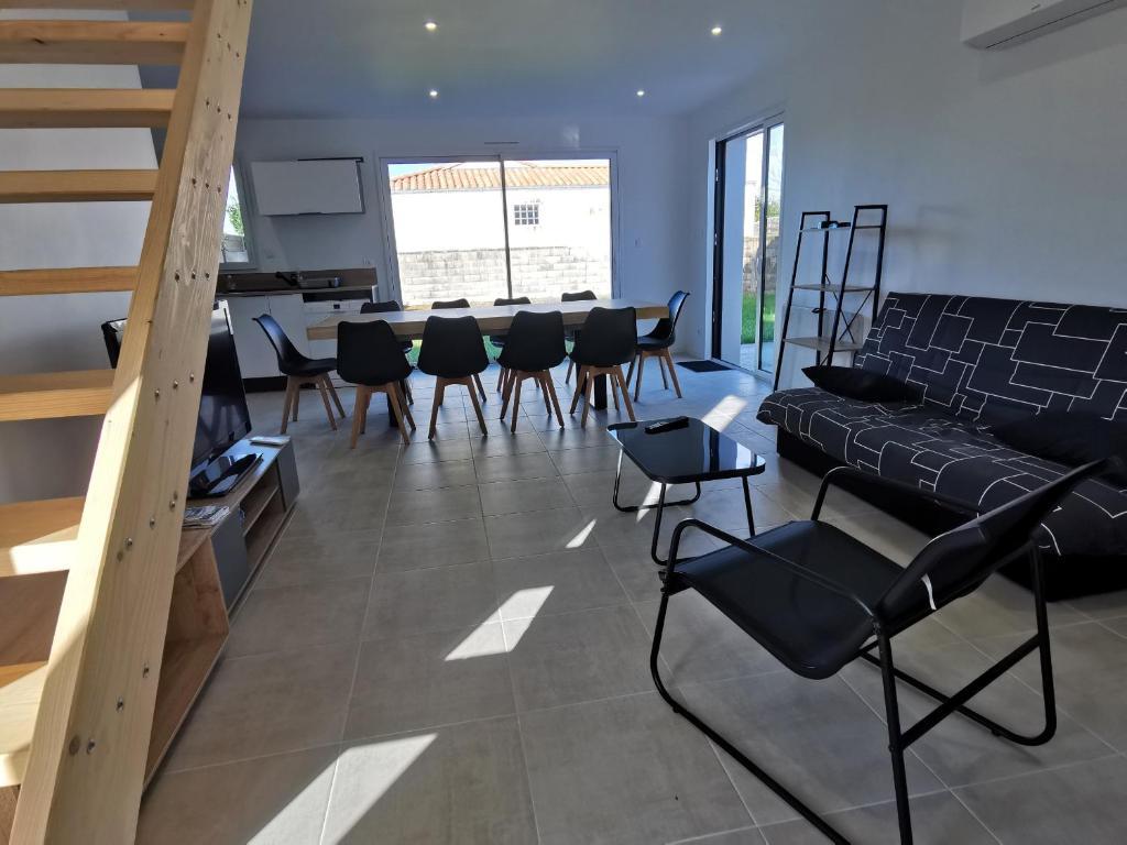 sala de estar con mesa y sillas y escalera en La Maison Manole, en Jard-sur-Mer