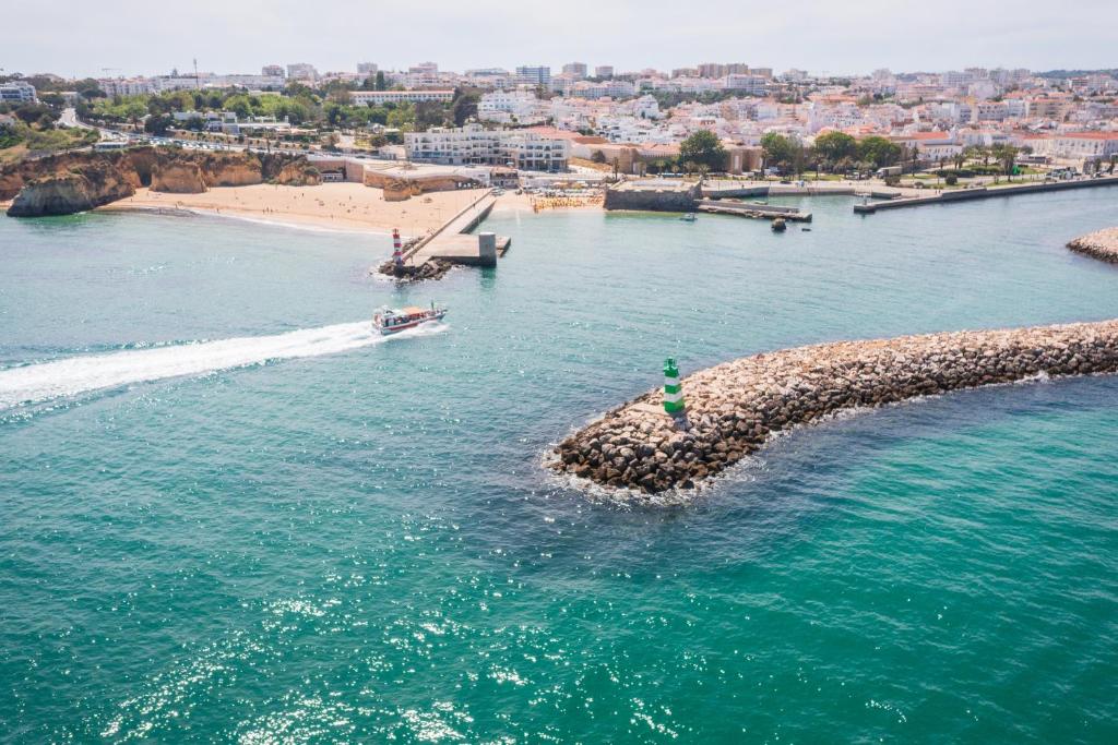 a boat in the water next to a beach at Fábrica da Ribeira 71 by Destination Algarve in Lagos