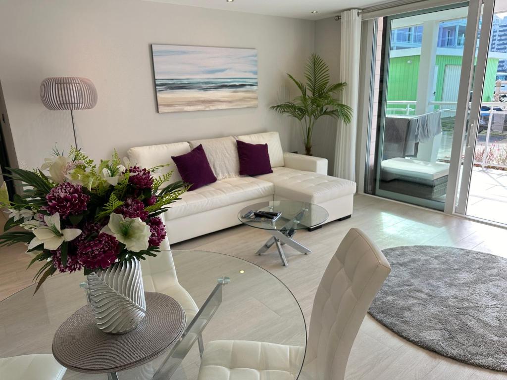 a living room with a couch and a table with a vase of flowers at Marina Club - Luxury Apartment in Ocean Village with Parking in Gibraltar