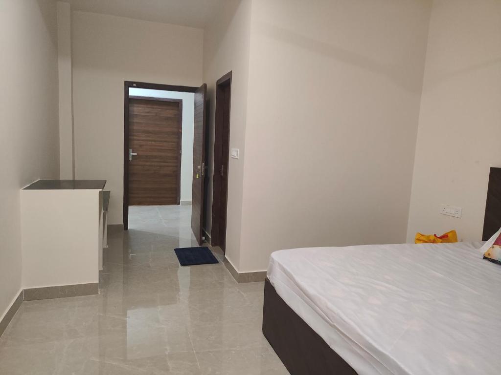 1 dormitorio con 1 cama y puerta que da a un pasillo en Uma Magan Farms, en Vrindāvan