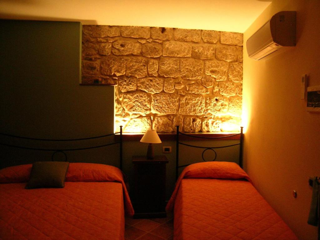 a bedroom with two beds and a stone wall at Domus Lilio in Petralia Sottana