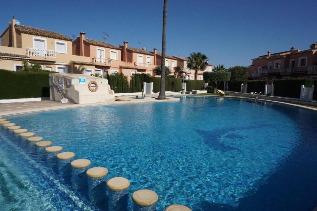 uma grande piscina com água azul e alguns edifícios em Casa del Sol in Els Poblets em Els Poblets