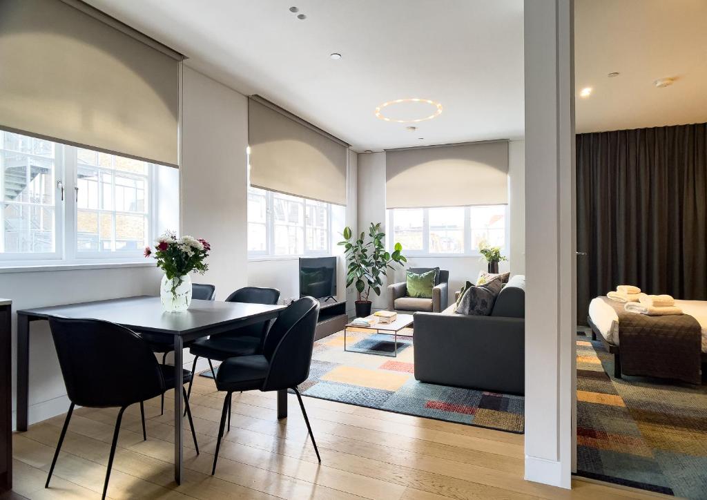 a dining room and living room with a table and chairs at Mirabilis Apartments - Bayham Place in London